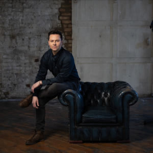 Christopher Marney sat on the arm of a sofa.